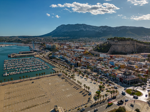 This aerial drone photo shows the coastal town of Denia in the Costa Blanca, Spain. There is a beautiful castle on top of a hill in the city centre.