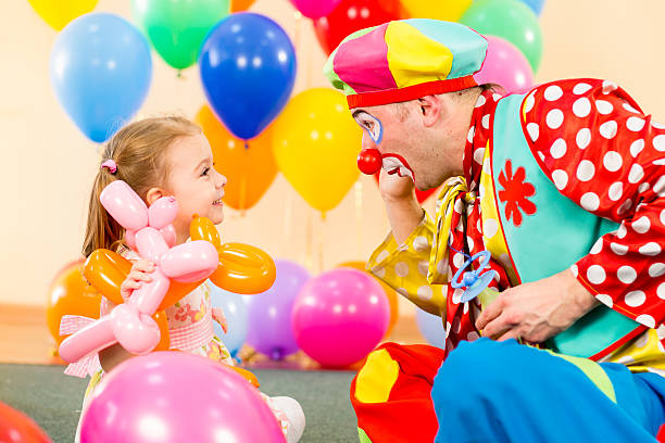 Cтоковое фото Счастливый ребенок девочка и Клоун играет на день рождения