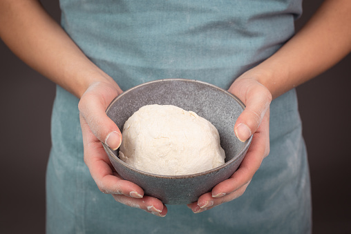 Fresh wheat dough, baker holds bowl with flour, bread or pizza, prepare ingredients for food, baking pastry