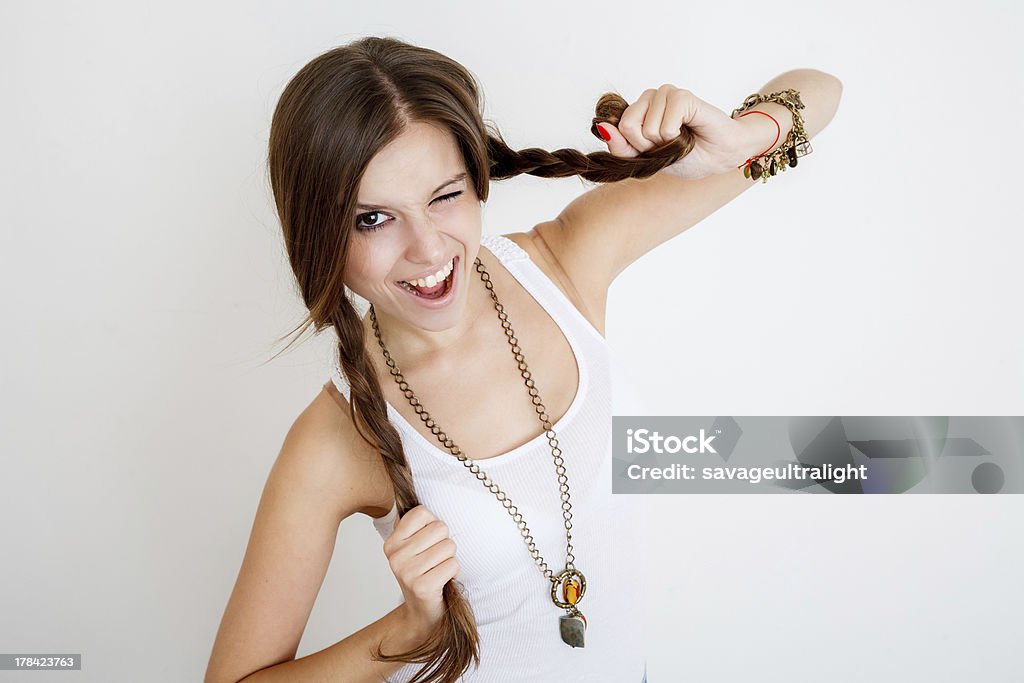 Giovane donna giocare con Lei trecce - Foto stock royalty-free di Abbigliamento casual