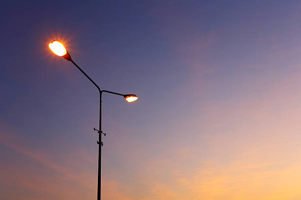 feu éclairé au coucher du soleil - street light photos et images de collection