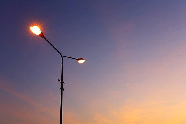 luz de rua iluminada ao pôr-do-sol - poste - fotografias e filmes do acervo