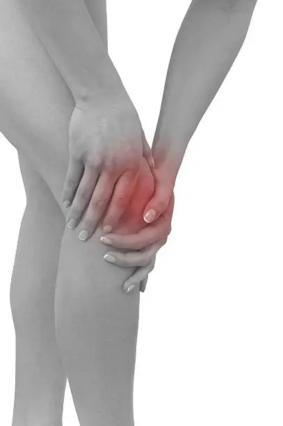 Acute pain in a woman  knee. Female holding hand to spot of knee-aches. Concept photo with Color Enhanced blue skin with read spot indicating location of the pain. Isolation on a white background.