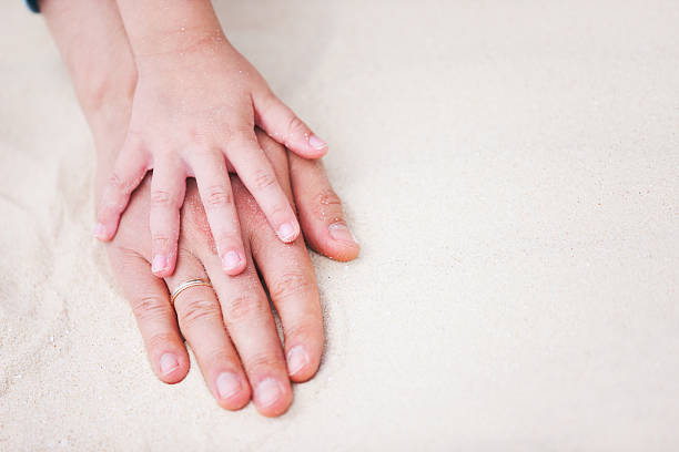 istock Father and daughter hands on sand 178426315
