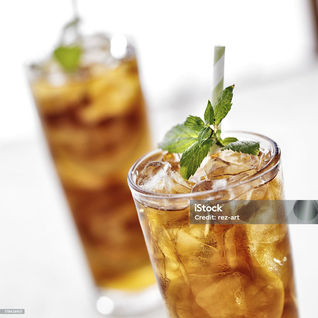 two ice cold glasses of iced tea with mint close up photo of two cold glasses of iced tea with mint garnish. Shot with selective focus. Brown Stock Photo