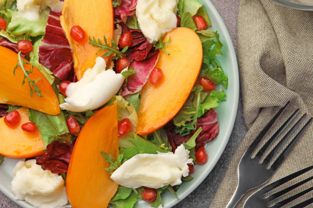 istock Delicious persimmon salad with cheese and pomegranate on cloth, flat lay 1784272127