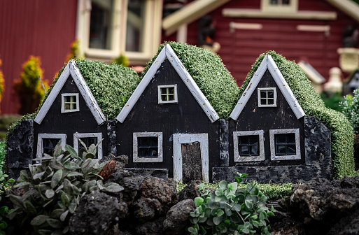 Three small black toy wooden elf homes, typical decoration in the gardens in Iceland.