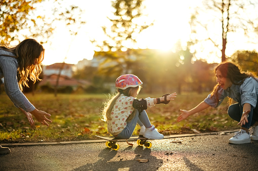 Two women are having fun with a little girl in the park