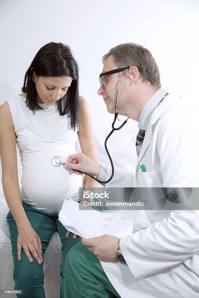 Médico usando o Estetoscópio em mulher grávida - Foto de stock de 30 Anos royalty-free