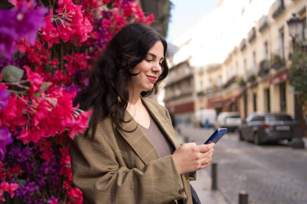 istock Young businesswoman using phone standing next to a floral wall 1784279977