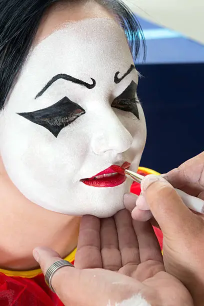 Pierrot clown woman getting her face painted