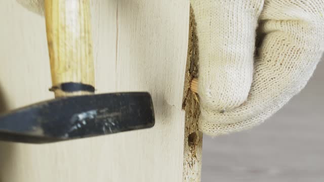 A worker hammers a wooden dowel into a hole of a smaller diameter and breaks a piece of furniture.