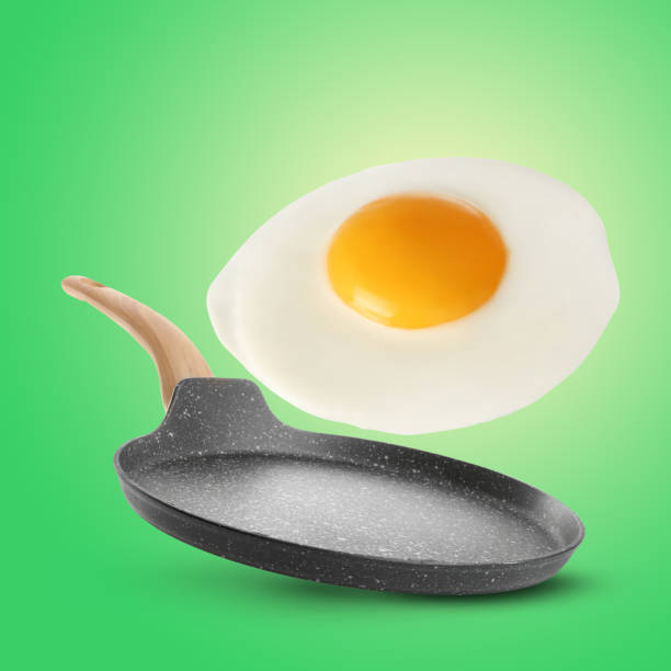 istock Tasty fried chicken egg falling into frying pan on color background 1784284861