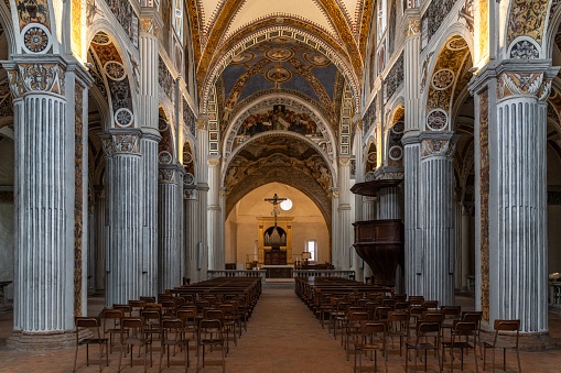 A majestic church interior with an abundance of wooden chairs and golden accents in Italy
