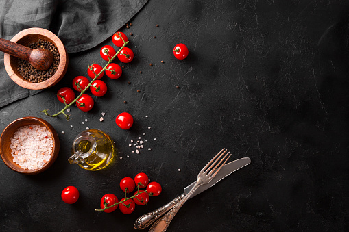 Food background, spices, tomatoes and oil on a black background, free space for text