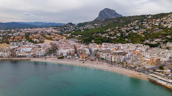 This aerial drone photo shows the coastal town of Javea/Xabia in the Costa Blanca in Spain. The small town has a beautiful boulevard and beach and there is also a marina.