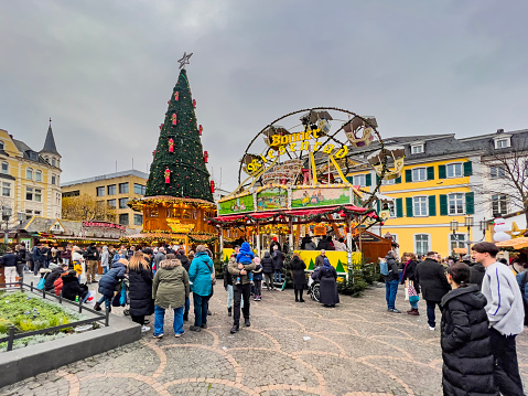 Bonn, Germany, 12/03/2022: Happy people are walking around the Christmas Market square and the Ferris wheel.