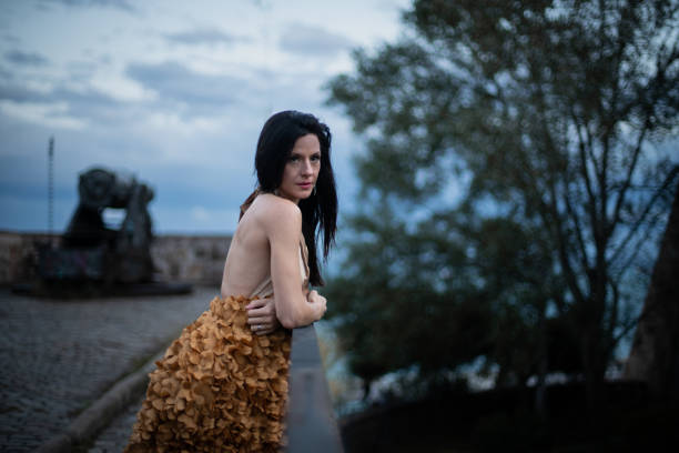 istock Woman in Elegant Dress on a Castle at Susnet. 1784314380