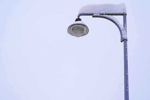 Street lantern covered with thick layer of snow captured in low angle view. It shows heavy snowfall in January 2021 in Urdorf, Switzerland. Around there is a lot of copy space.