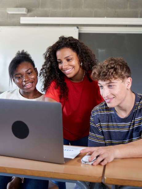 istock Group of multiracial student friends sharing a laptop during class to do an assignment. 1784321763