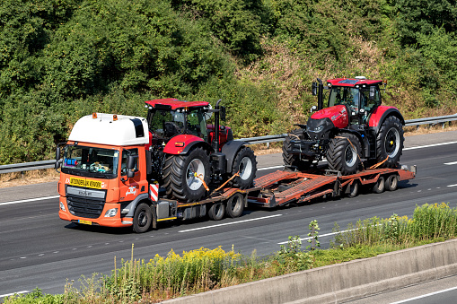 Cologne, Germany - July 13, 2018: Flatbed truck with two farm tractors on motorway