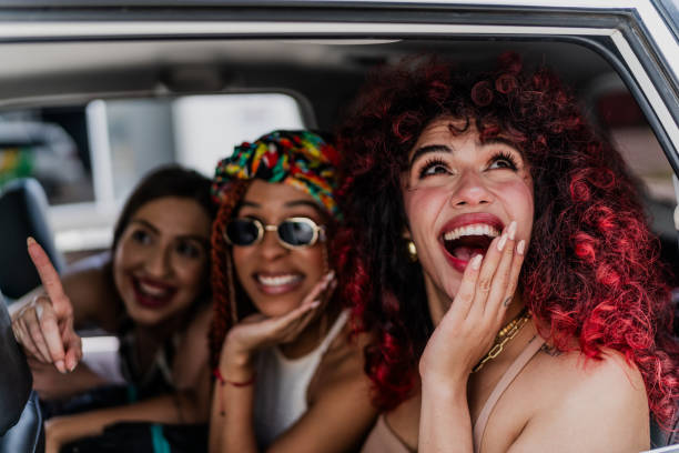 Happy female friends looking at view in a taxi Happy female friends looking at view in a taxi car city urban scene commuter stock pictures, royalty-free photos & images