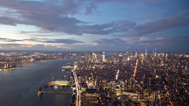 Aerial shot of New York City skyline and Hudson River at dawn on a cloudy day.