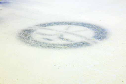 Close-up view of hockey emblem with sticks and puck beneath surface of ice rink. Texture or background option.