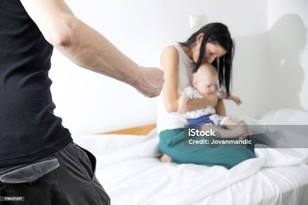 A young woman and her baby frightened by a violent man woman and child is the victim of aggressive man Domestic Violence Stock Photo