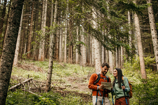 A couple with backpacks strolls through the woods, symbolizing the harmony between human connection and the great outdoors
