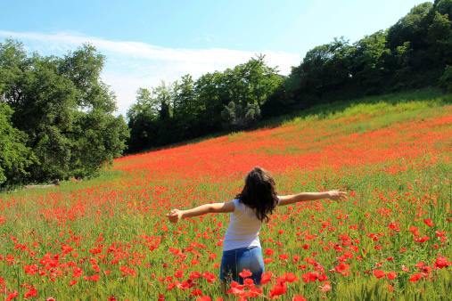 A teenage girl enjoy springtime in a poppy field.