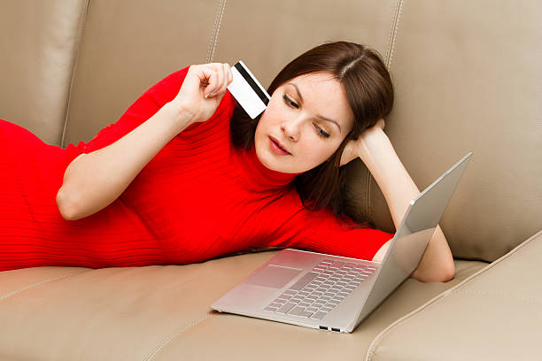 Beautiful woman lying on the sofa with laptop. stock photo