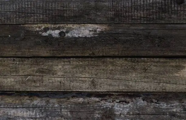 A captivating image featuring evenly arranged aged pine planks, showcasing a range of wood colors influenced by the elements: rain, sun, and wind. The symmetrical pattern is shot perpendicular to the boards, revealing their natural weathered beauty.