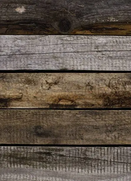 A captivating image featuring evenly arranged aged pine planks, showcasing a range of wood colors influenced by the elements: rain, sun, and wind. The symmetrical pattern is shot perpendicular to the boards, revealing their natural weathered beauty.