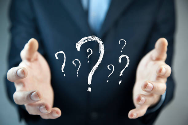Businessman on blurred background holding hand drawn question marks/