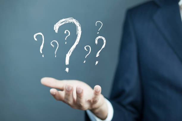Businessman on blurred background holding hand drawn question marks/