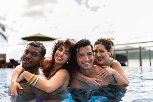 Portrait of happy friends in the pool at hotel