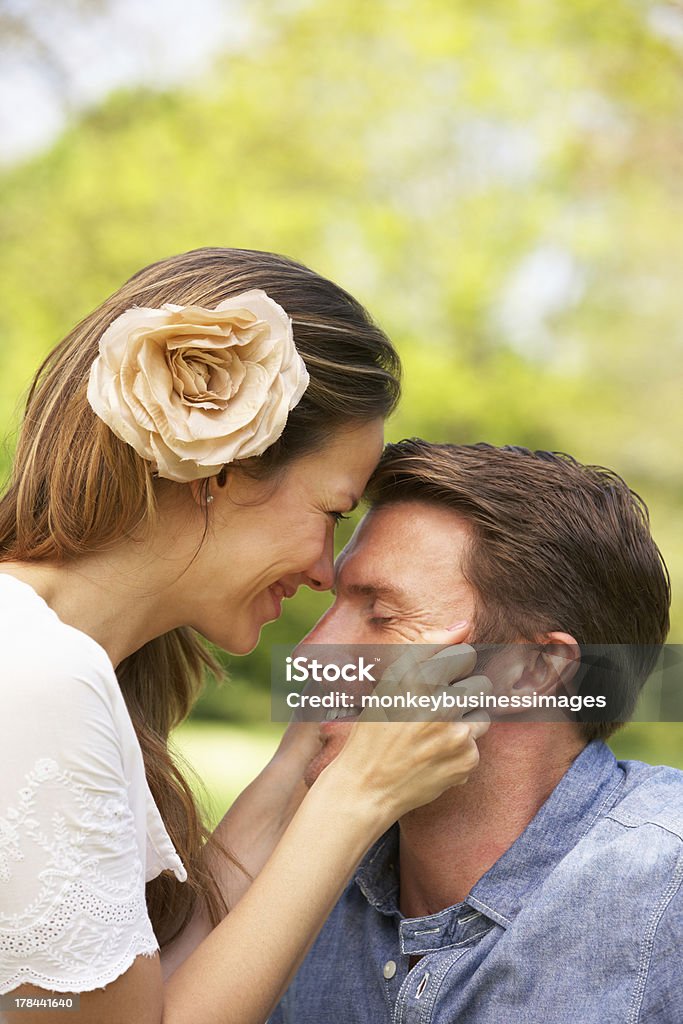 Romantic Couple Sitting In Field Of Summer Flowers Romantic Couple Sitting In Field Of Summer Flowers Looking At Each Other Smiling 30-39 Years Stock Photo