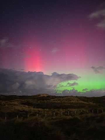 Northern lights (Aurora borealis) with vibrant pink, purple and green colors in north to northwesterly direction, viewed from The Netherlands.