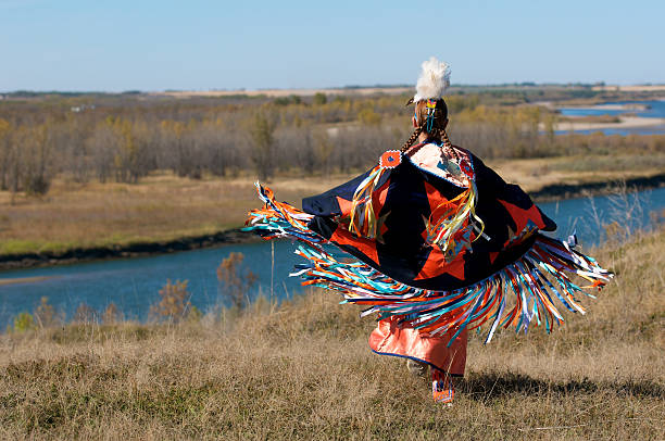 Woman's Fancy Shawl Dancer A woman performing a First Nations fancy shawl dance in a field alongside the river in Saskatoon, Saskatchewan indegious culture stock pictures, royalty-free photos & images