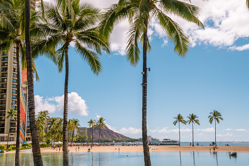 Honolulu, Oahu, HI, US-October 29, 2023: The famous Waikiki Beach with palm trees and Diamond Head in background.
