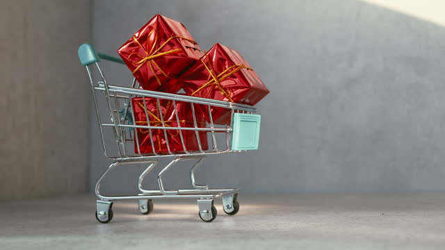 Gift Shopping. Metal supermarket shopping cart with wrapped red gift boxes