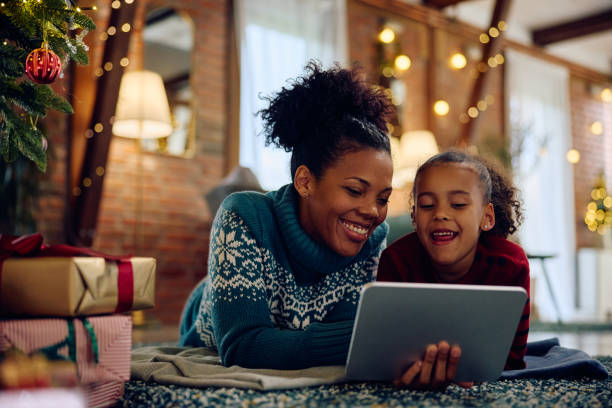 istock Happy black mother and daughter using digital tablet at Christmas at home. 1784440879