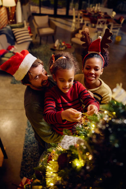 istock Happy family decorating Christmas tree at home. 1784443563