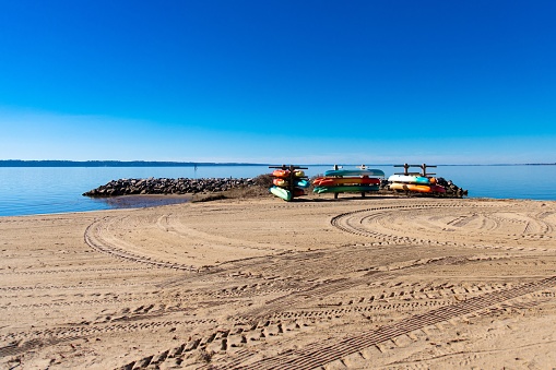 Two boats resting on the sand of a tranquil beach, their sails furled against a bright blue sky