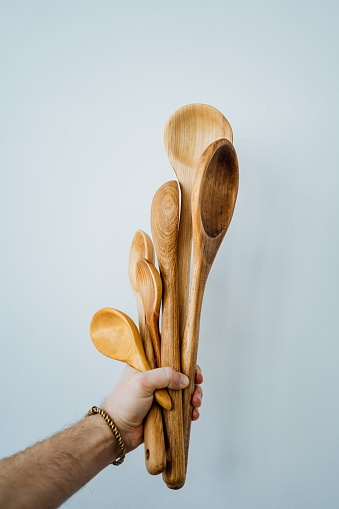 The model holds six wooden spoons in her hand. All spoons are of different sizes. High quality photo
