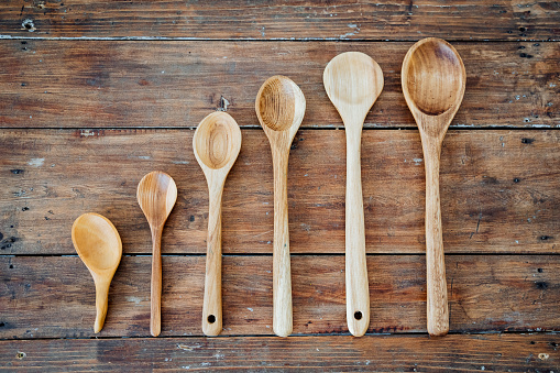 Wooden spoons of different sizes and lengths lie on the table. There are six spoons in total. High quality photo