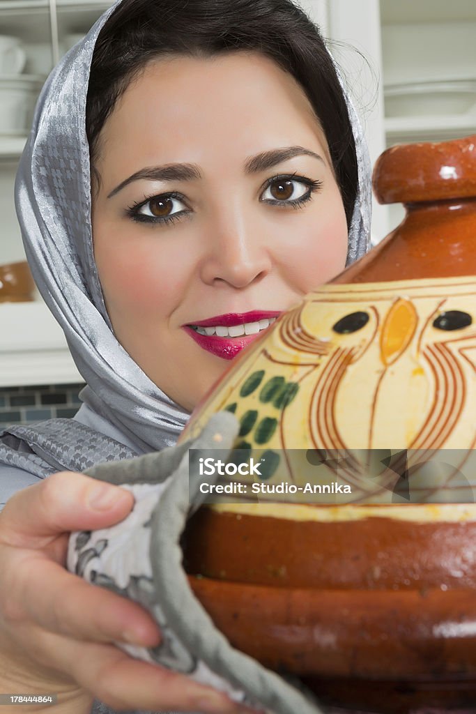 Traditional tajine dish Traditional Moroccan immigrant woman in Europe cooking tajine during Ramadan in her modern kitchen Adult Stock Photo