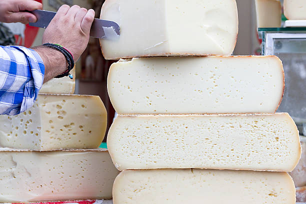 Graviera cheese A stack of traditional, large Cretan graviera cheeses on display at a farmers' market portion cut out cheese part of stock pictures, royalty-free photos & images