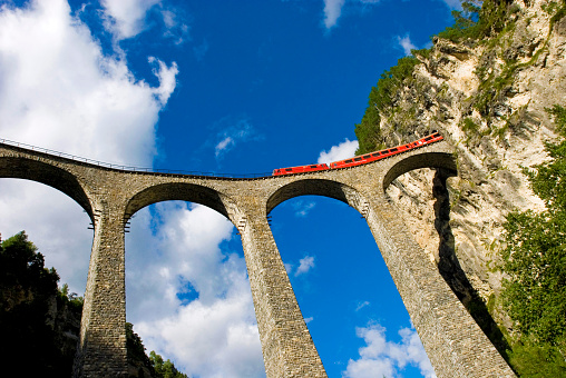 red train of Raethian Railway Company on Viaduct which is a UNESCO world cultural heritage on the route Albula to Bernina